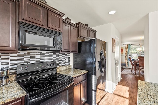 kitchen featuring dark brown cabinetry, light stone countertops, light hardwood / wood-style flooring, and black appliances