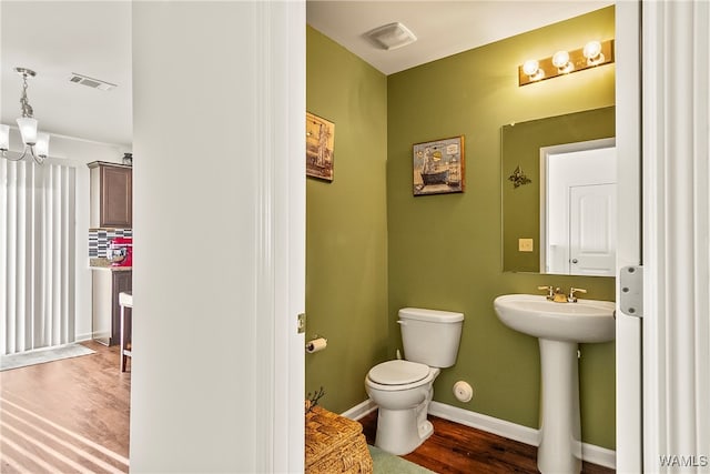 bathroom with hardwood / wood-style flooring, backsplash, toilet, and sink