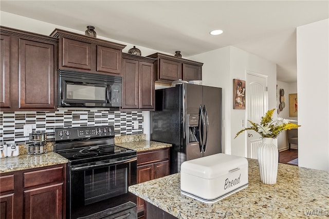 kitchen featuring decorative backsplash, hardwood / wood-style flooring, light stone countertops, and black appliances