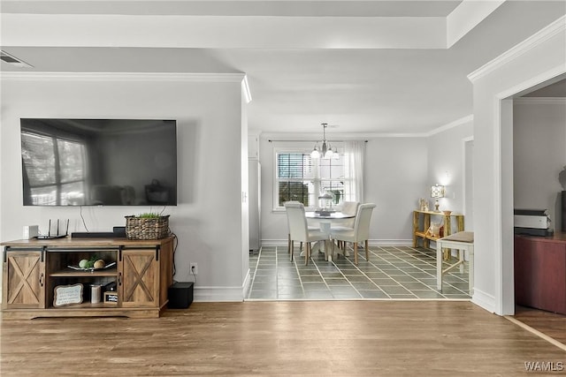 dining room featuring visible vents, ornamental molding, wood finished floors, a chandelier, and baseboards