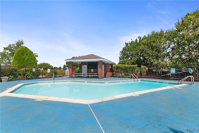 community pool featuring a patio area, fence, and an outdoor structure