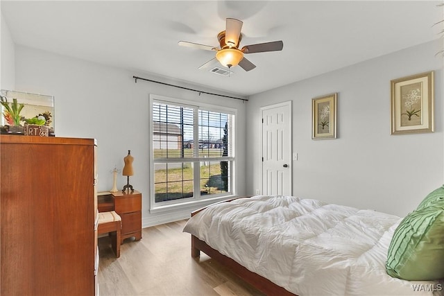 bedroom with light wood-style floors, visible vents, and a ceiling fan