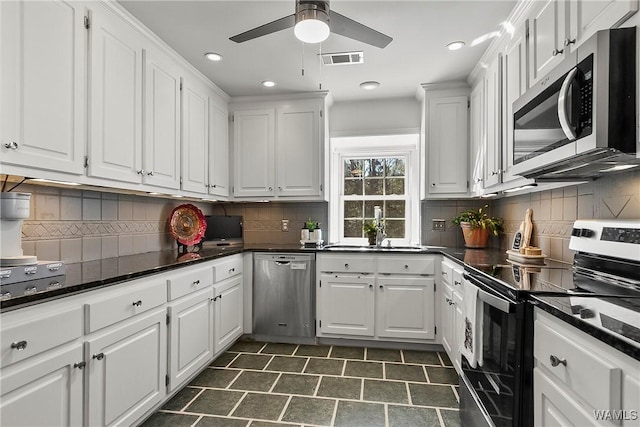 kitchen with stainless steel appliances, dark countertops, white cabinetry, and visible vents