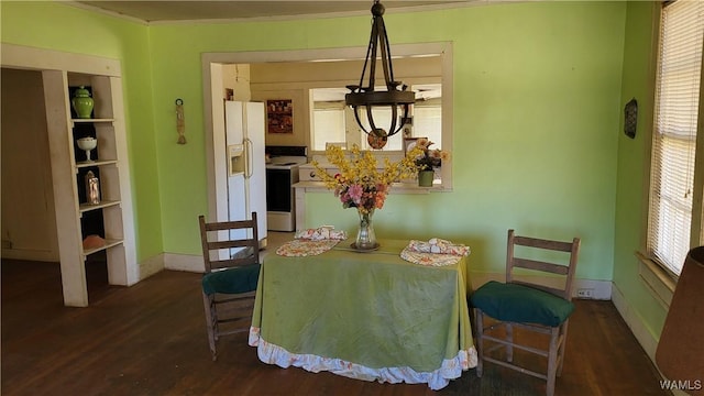 dining space with wood finished floors and crown molding