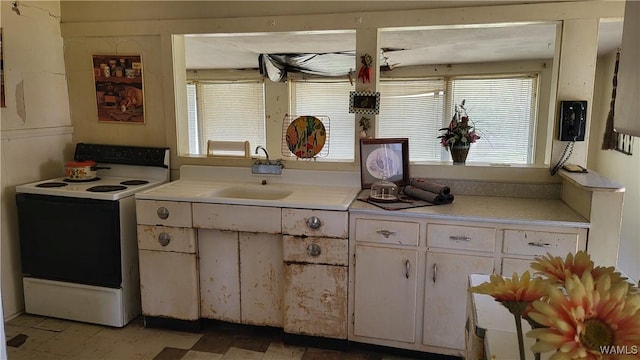 kitchen featuring light countertops, white range with electric cooktop, a sink, and white cabinetry