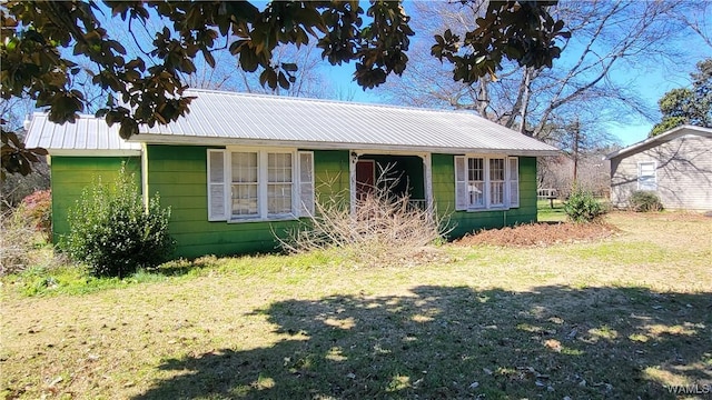 view of front of property featuring metal roof and a front yard