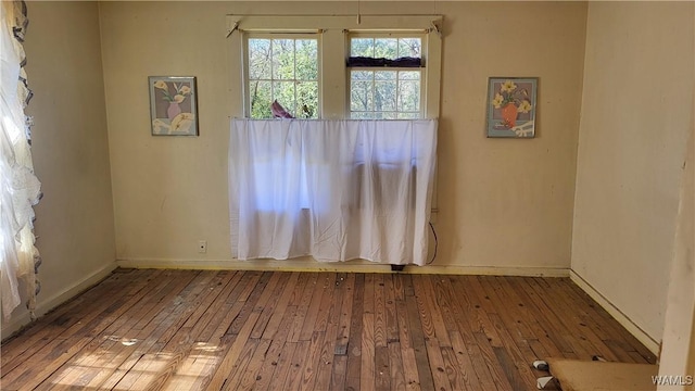 empty room featuring hardwood / wood-style flooring and baseboards