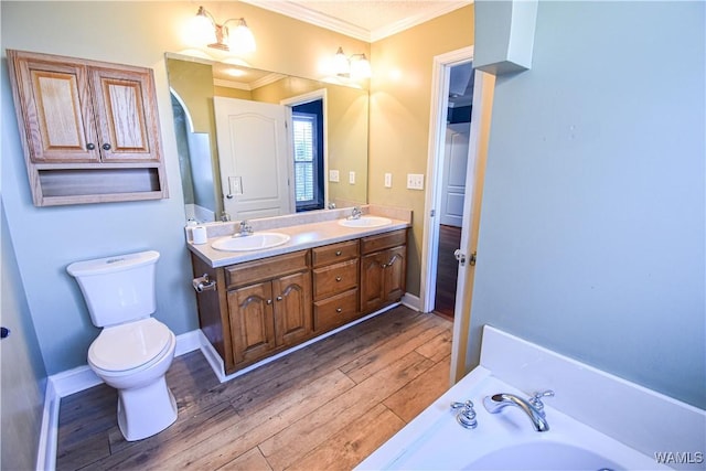 bathroom featuring vanity, a bathing tub, hardwood / wood-style flooring, toilet, and ornamental molding