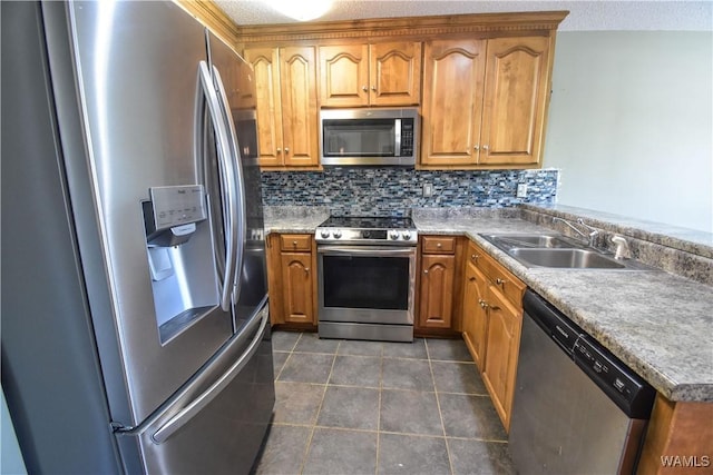 kitchen featuring appliances with stainless steel finishes, tasteful backsplash, a textured ceiling, dark tile patterned floors, and sink