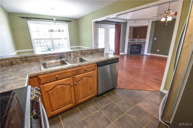 kitchen featuring dishwasher, sink, stove, pendant lighting, and ceiling fan with notable chandelier