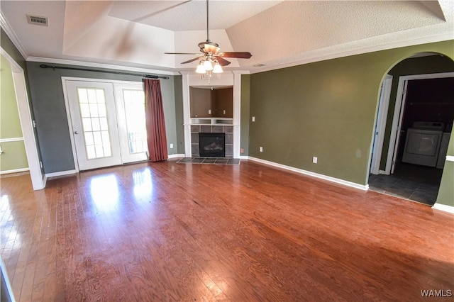 unfurnished living room featuring ornamental molding, a tray ceiling, ceiling fan, washer / clothes dryer, and a tiled fireplace