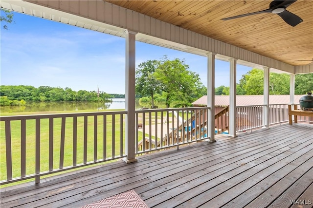 wooden terrace featuring a water view, ceiling fan, a lawn, and view of scattered trees
