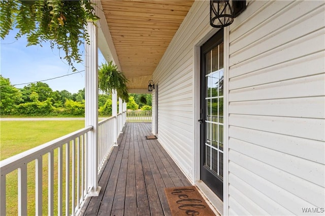 wooden terrace featuring a porch and a lawn