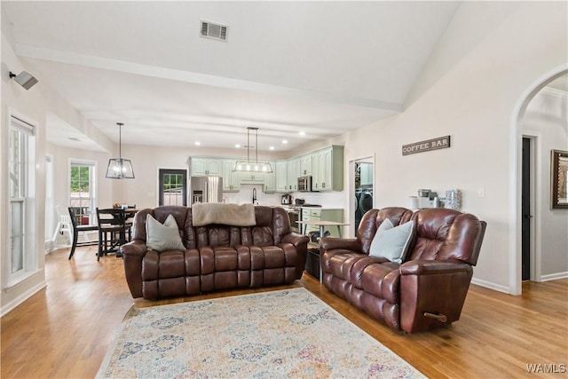 living room featuring light wood finished floors, arched walkways, baseboards, recessed lighting, and lofted ceiling