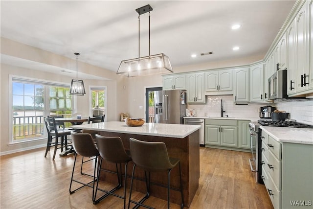 kitchen featuring stainless steel appliances, a center island, light wood finished floors, a sink, and recessed lighting