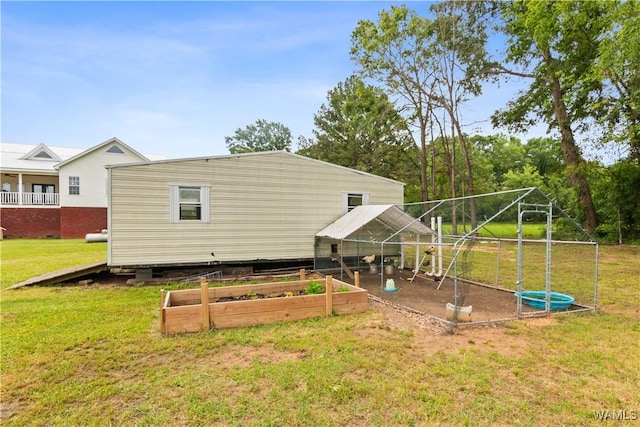 back of property featuring a lawn, a vegetable garden, an outbuilding, and exterior structure