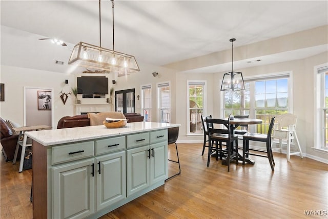 kitchen with a center island, light wood-type flooring, open floor plan, decorative light fixtures, and a breakfast bar