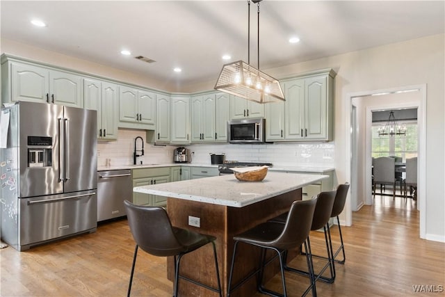 kitchen with appliances with stainless steel finishes, decorative backsplash, a sink, wood finished floors, and recessed lighting