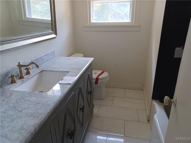 bathroom featuring toilet, a wealth of natural light, vanity, and baseboards