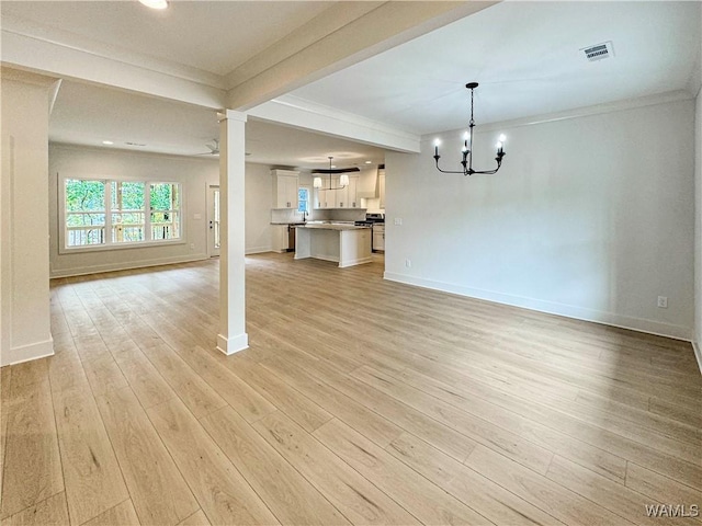 8 Northside Rd, Berry, AL 35546 - unfurnished living room featuring light wood-type flooring, crown molding, baseboards, a chandelier, and ornate columns