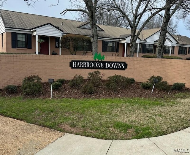 community / neighborhood sign featuring fence and a yard