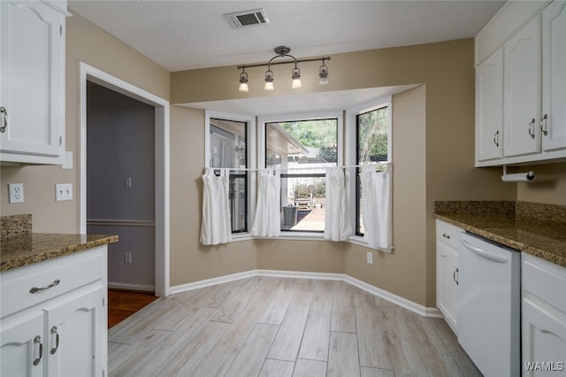 kitchen featuring white cabinets, light wood-type flooring, white dishwasher, and dark stone counters