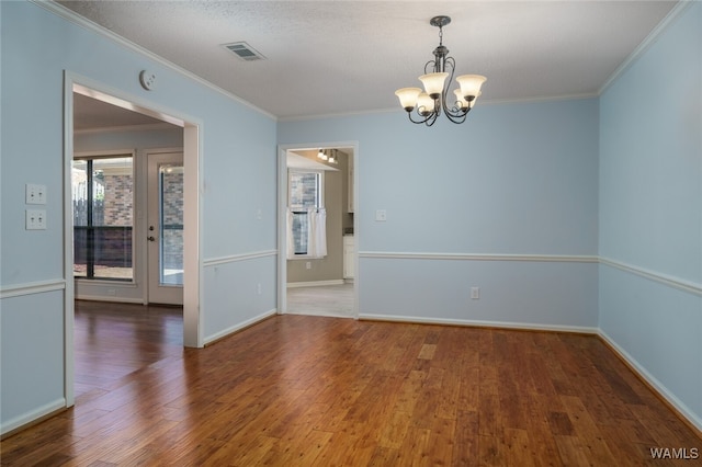 spare room with crown molding, dark wood-type flooring, a chandelier, and a textured ceiling