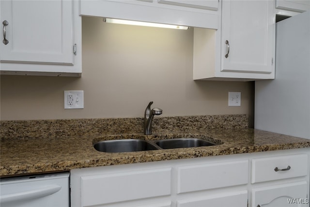 kitchen with dishwasher, dark stone countertops, white cabinetry, and sink