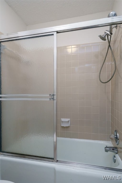 bathroom featuring a textured ceiling, toilet, and bath / shower combo with glass door