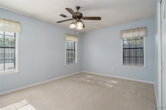 unfurnished room with light colored carpet, a wealth of natural light, and ceiling fan