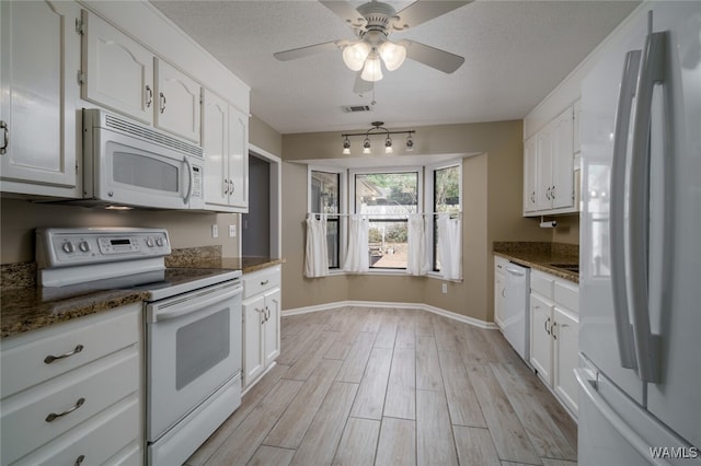 kitchen with white cabinetry, light hardwood / wood-style flooring, dark stone counters, and white appliances