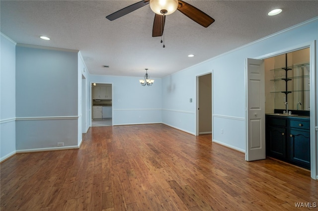 unfurnished living room featuring wood-type flooring, ceiling fan with notable chandelier, a textured ceiling, and ornamental molding