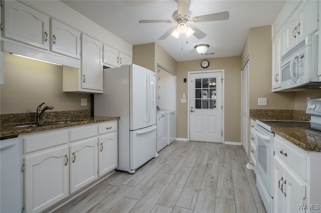 kitchen with white appliances, washer and clothes dryer, sink, light hardwood / wood-style flooring, and white cabinets