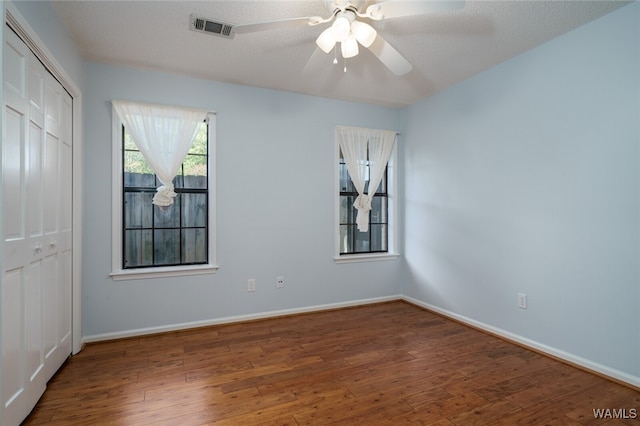 empty room with a textured ceiling, dark hardwood / wood-style flooring, and ceiling fan