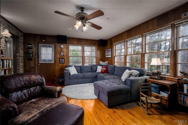 1428 Plymouth Ln, Tuscaloosa, AL 35406 - living area featuring a ceiling fan, wood finished floors, wood walls, a textured ceiling, and brick wall