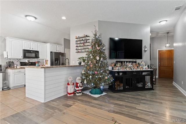 kitchen with hanging light fixtures, stainless steel fridge with ice dispenser, kitchen peninsula, white cabinets, and light wood-type flooring