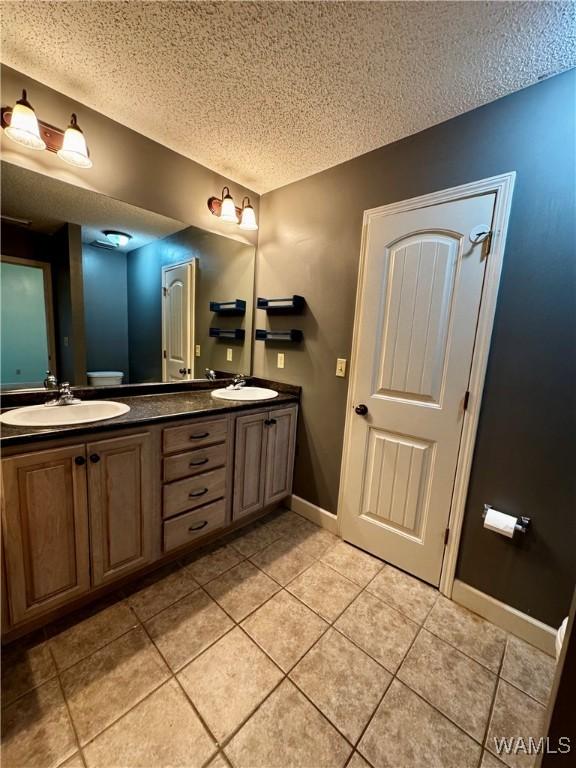 bathroom featuring a textured ceiling, vanity, toilet, and tile patterned floors