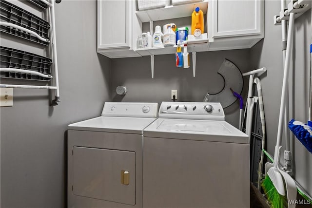 clothes washing area featuring cabinets and washing machine and clothes dryer