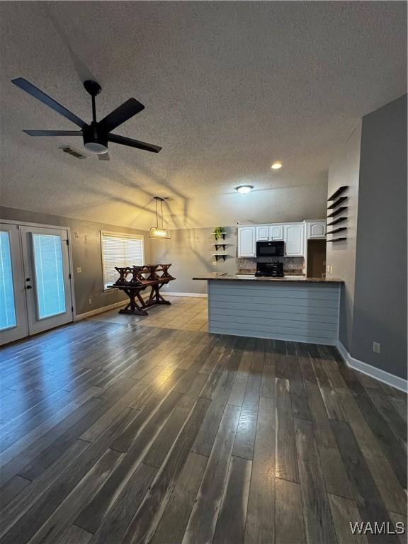 kitchen featuring sink, hanging light fixtures, lofted ceiling, white cabinets, and black appliances