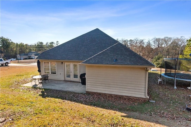 back of house with french doors, a yard, a trampoline, and a patio area