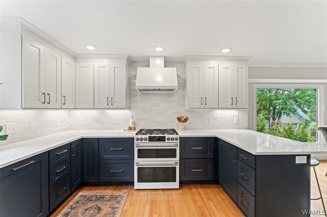 kitchen with white cabinets, a kitchen breakfast bar, double oven range, and exhaust hood