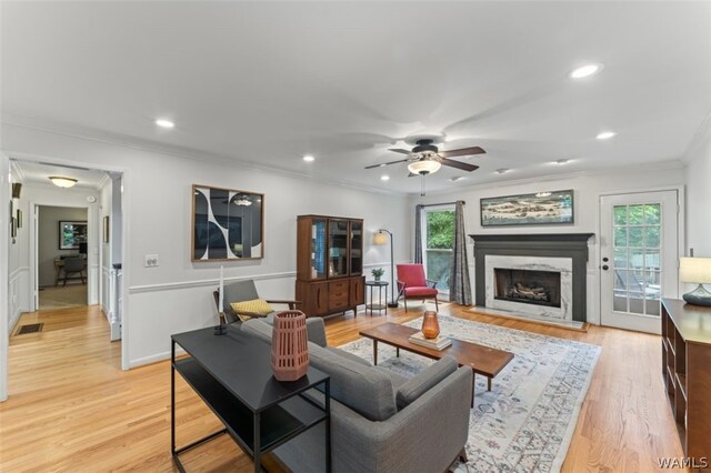 living room featuring ceiling fan, a healthy amount of sunlight, light wood-type flooring, and crown molding