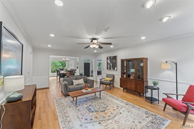 living room featuring ceiling fan with notable chandelier, light hardwood / wood-style floors, and ornamental molding