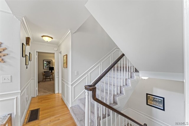 stairs featuring wood-type flooring and crown molding