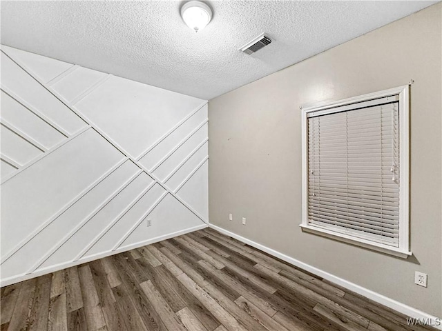 1902 45th Ave, Northport, AL 35476 - unfurnished room with baseboards, a textured ceiling, visible vents, and wood finished floors