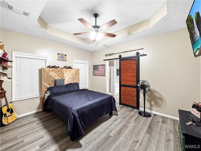 1902 45th Ave, Northport, AL 35476 - bedroom featuring a barn door, visible vents, a raised ceiling, and wood finished floors