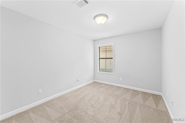 spare room featuring carpet, visible vents, and baseboards