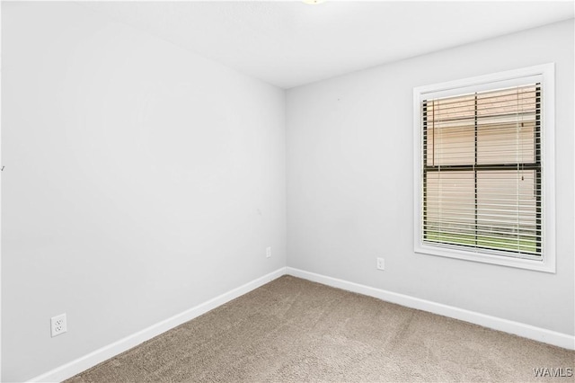 unfurnished room featuring carpet and baseboards