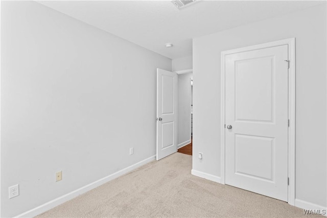 unfurnished bedroom featuring visible vents, baseboards, and light colored carpet