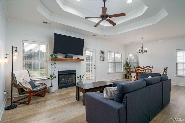 living room with crown molding, a tray ceiling, and light wood-type flooring